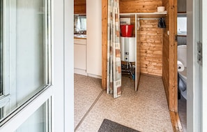 A compact kitchen with a sink, a red bucket, and a water heater.