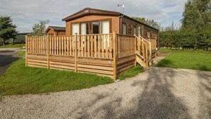 Ein Holz-Mobilheim mit Terrasse, überdachter Veranda und einem Schotterweg.