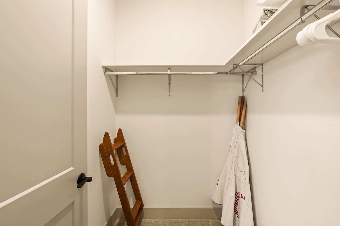 Een badkamer met een douche, een houten stoel, een handdoekhouder en een plank met toiletartikelen.