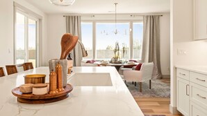 Een moderne keuken met een marmeren aanrecht, een houten eettafel en uitzicht op het omliggende landschap.