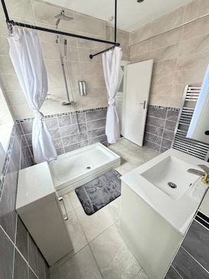 Ein Badezimmer mit Dusche, zwei Waschbecken, einer Badewanne und einem Handtuchhalter.