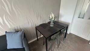 En matplats med ett bord, stolar, en vas med blommor och en grå soffa.