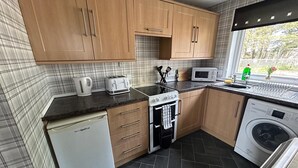 Ett kompakt kök med diskmaskin, mikrovågsugn, spis och tvättmaskin.