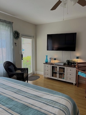 Ein Schlafzimmer mit Bett, Fernseher, Kommode und Stuhl.