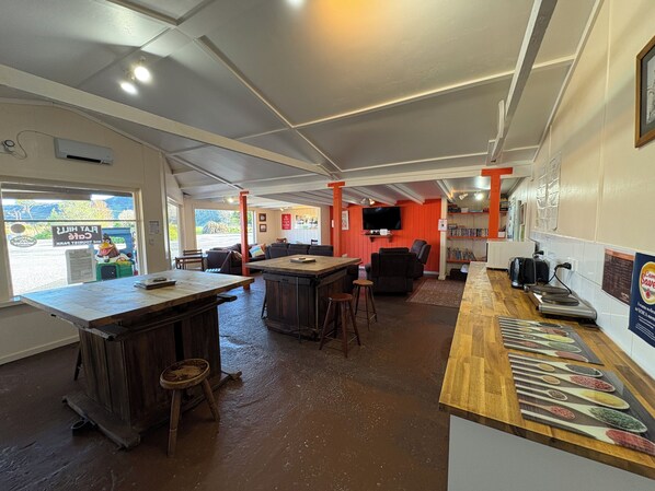 L’intérieur d’un restaurant, avec un bar, des tables et un téléviseur.