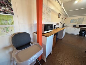 Une cuisine équipée d’un four à micro-ondes, d’une machine à café et d’une carte accrochée au mur.