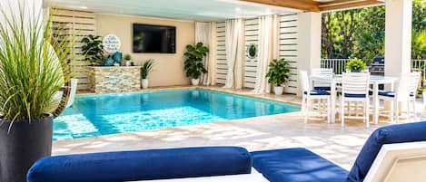 A poolside area with lounge chairs, a table, and potted plants.