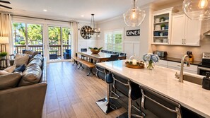 A modern kitchen with a central island, dining area, and a view of the outdoors.