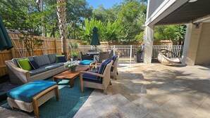 Eine Terrasse im Freien mit Korbmöbeln, einem Holztisch und einer Hängematte.