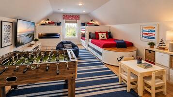 Habitación acogedora con mesa de fútbol, literas, escritorio con silla y ventana con vistas.