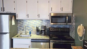 A kitchen with white cabinets, a stainless steel refrigerator, a microwave, a coffee maker, and a stove. - ML103 Cozy 2-bedroom first level condo in pleasant Snowshoe - Steps from slopes (Snowshoe)