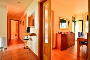A hotel corridor with a wooden reception desk, a dining area with chairs, and a tiled floor. - Fantastic house with pool 600m from Sa Riera beach (Begur)