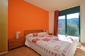 A bedroom with a bed, a nightstand, a window with curtains, and a view of greenery outside. - Fantastic house with pool 600m from Sa Riera beach (Begur)