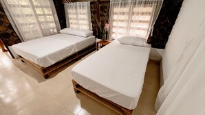 A room with two wooden beds, white linens, a small table with a vase, and a window with sheer curtains. - Tranquilidad Cabin, Left Hemisphere (San José Del Guaviare)