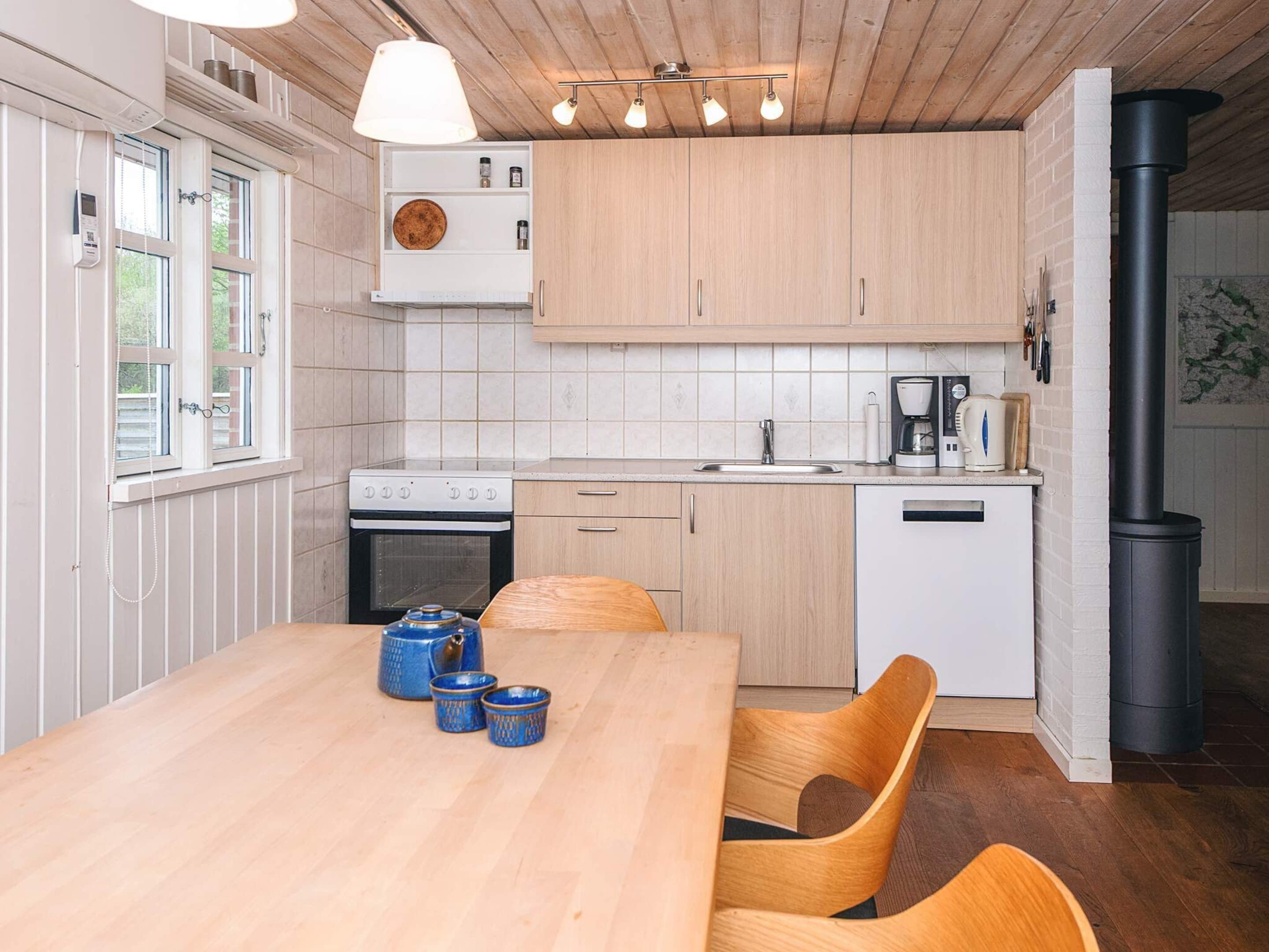 A modern kitchen with wooden cabinets, a stove, a sink, and a black stove pipe.