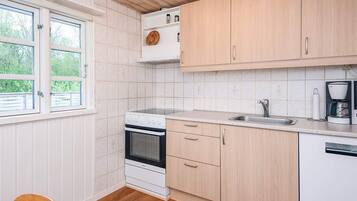 A kitchen with white cabinetry, a built-in oven, a sink, and a coffee maker.