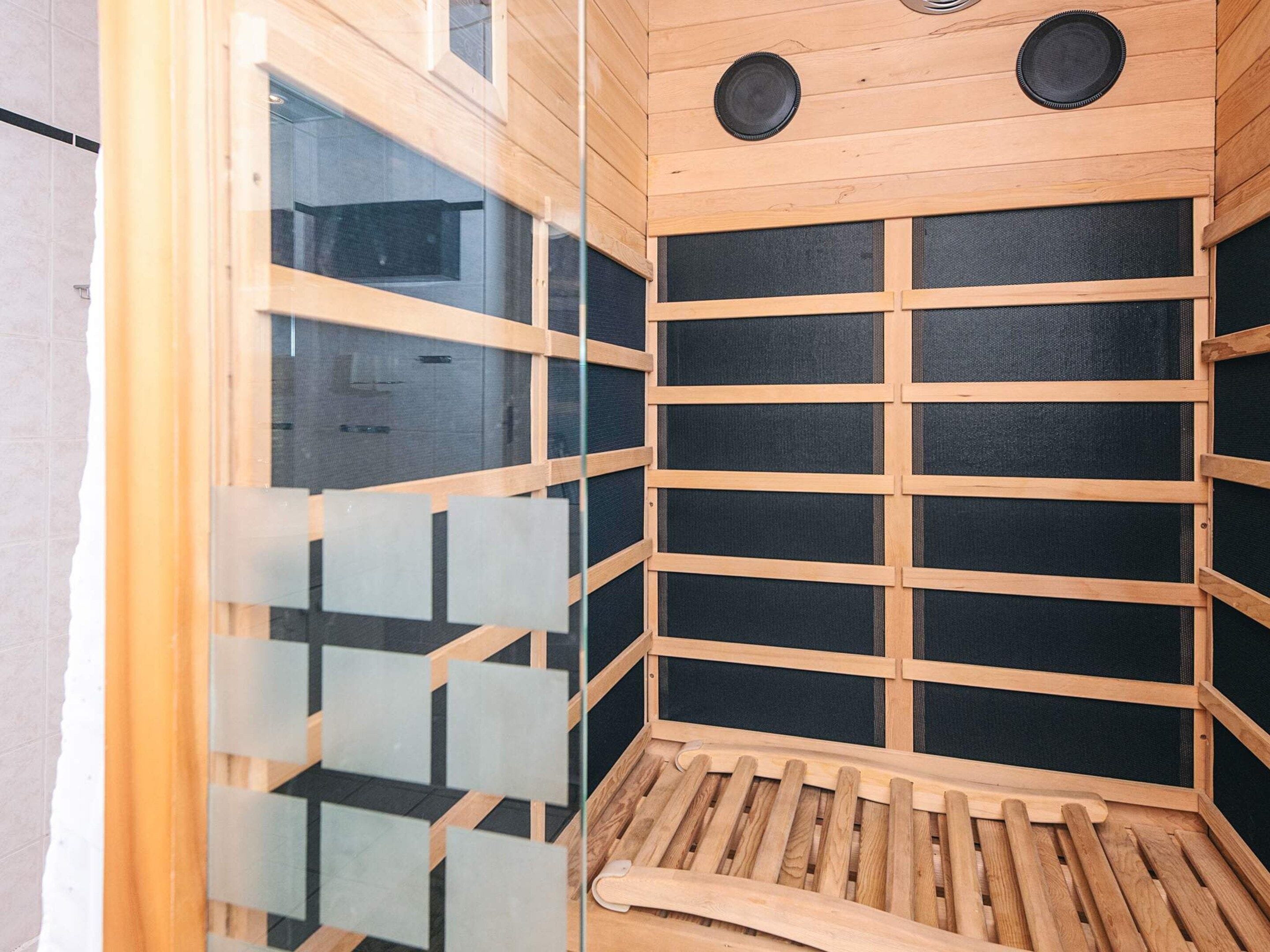 A wooden interior with a grid-like structure, possibly a sauna or steam room, with a bench and a small table.