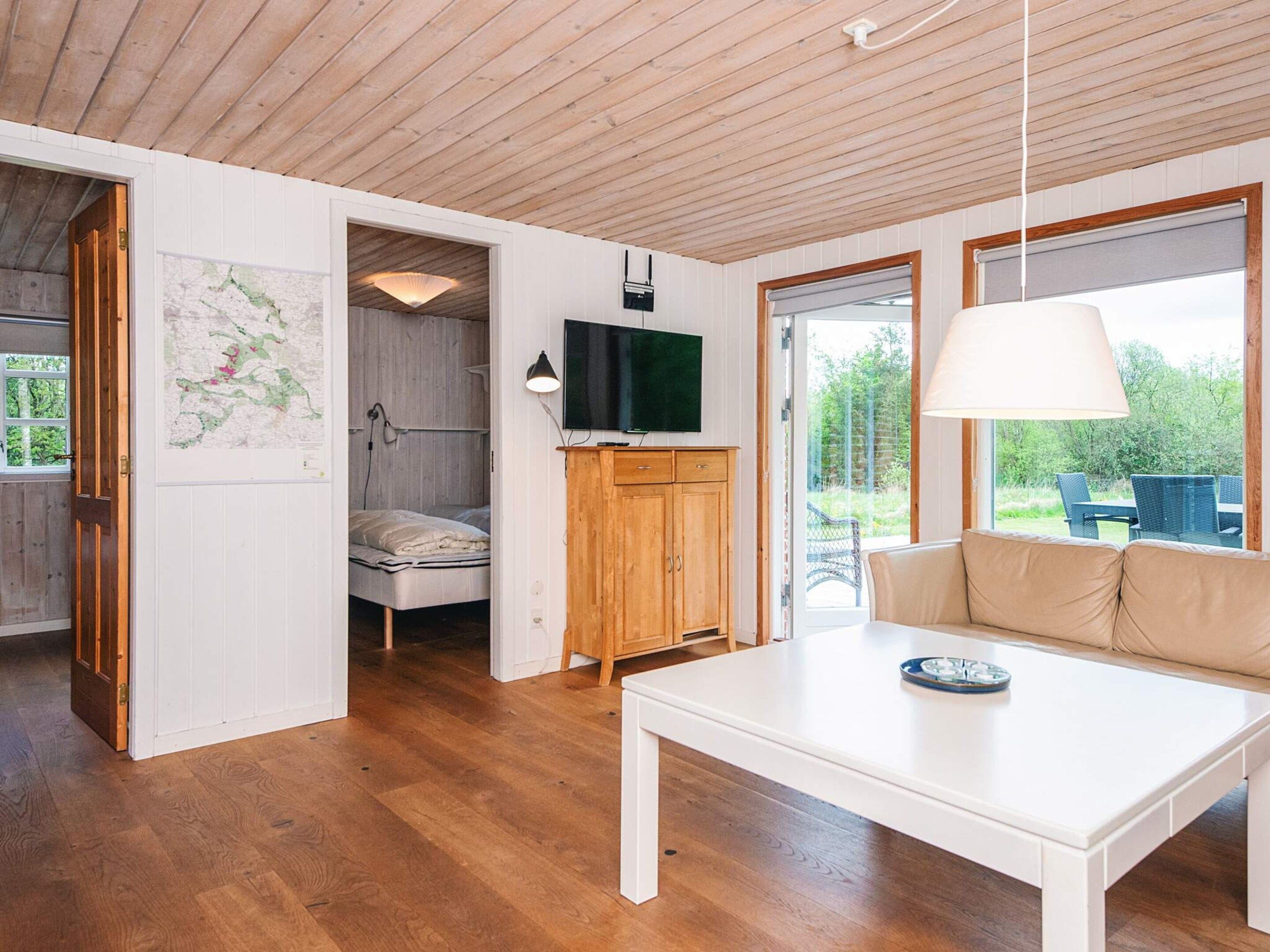 A modern interior with a wooden ceiling, a white table, a sofa, a TV, and a map on the wall.