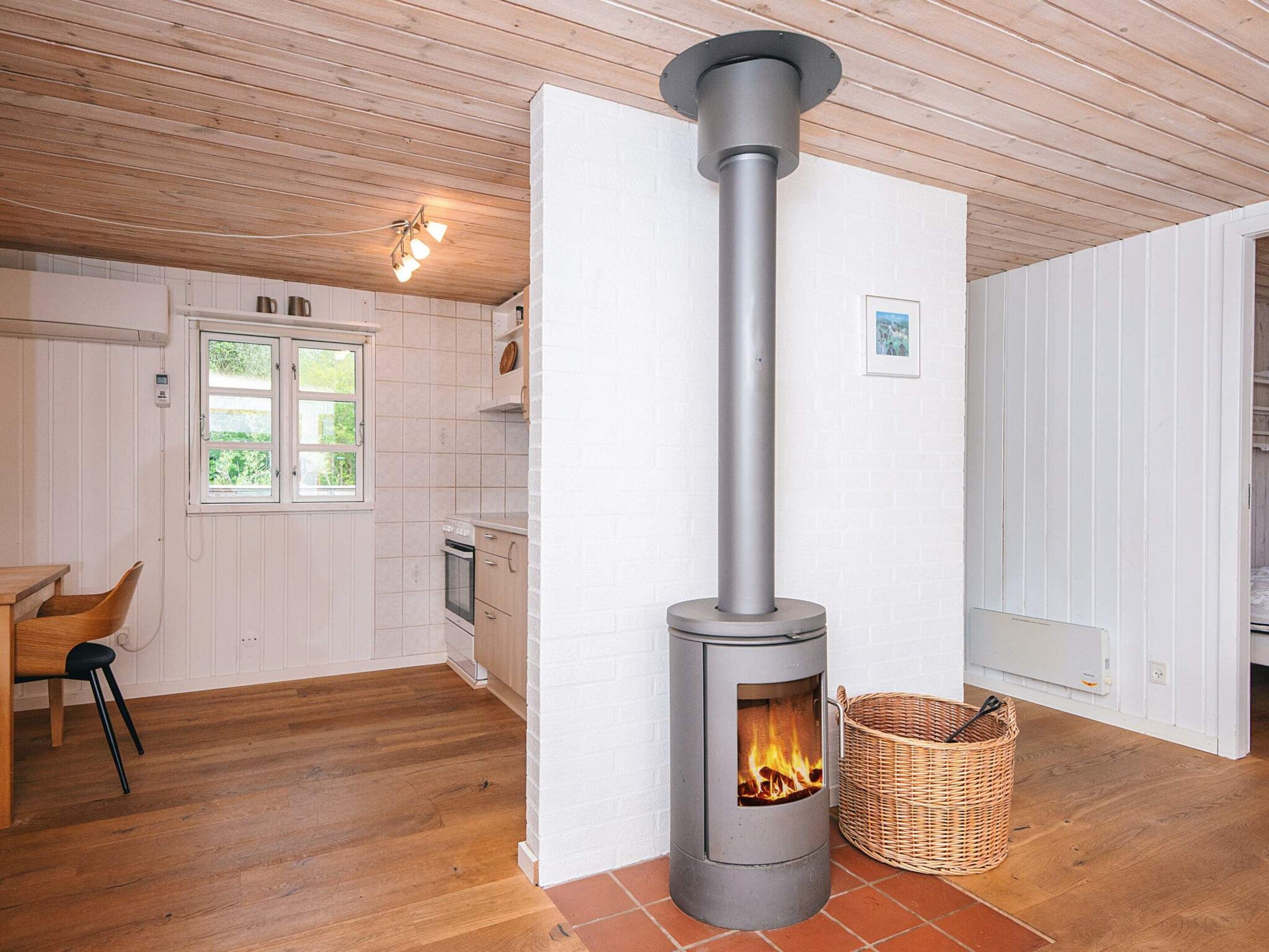 A modern kitchen with a central stove, wooden flooring, and a white interior.