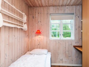 A room with wooden walls, a bed with white bedding, a red wall-mounted lamp, and a window with a view of greenery. - 5 Person Holiday Home in Herning (Herning)