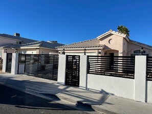 A residential area with houses, a gated driveway, and a clear blue sky. - Private 2BR Home Near the Las Vegas Strip, Wi-Fi, Laundry and Parking. (Las Vegas)