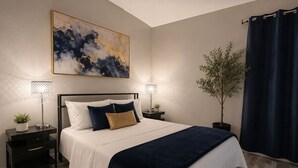 A bedroom with a bed, two bedside tables, a nightstand, a potted plant, and a large abstract painting. - Private 2BR Home Near the Las Vegas Strip, Wi-Fi, Laundry and Parking. (Las Vegas)