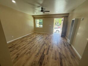 A spacious room with wooden flooring, a ceiling fan, and a door leading outside.
