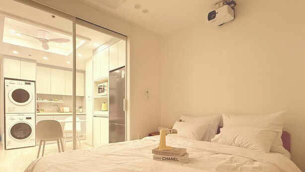 A bedroom with a bed, pillows, a nightstand, and a book titled 'Coco Chanel Paris'. - Esanghan Stay Suwon Ingye (Suwon)