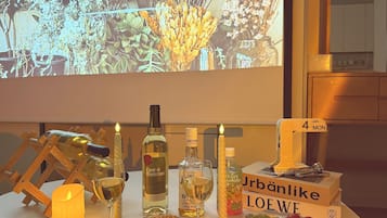 A table set with various bottles, glasses, and a candle, with a projection screen in the background displaying the word 'essential.'