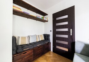 Una habitación con una puerta de madera oscura, un banco empotrado con cojines y una estantería de madera encima.