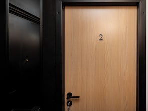A wooden door with a number '2' and a keyhole, part of a black-framed structure. - Lermontowa Comfort Room #2 (Łódź)