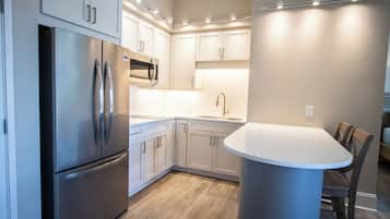 A modern kitchen with stainless steel appliances, white cabinetry, and a central island with seating.