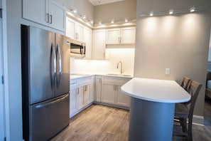 Une cuisine moderne dotée d’appareils électroménagers en acier inoxydable, de meubles blancs et d’un îlot central avec des sièges.