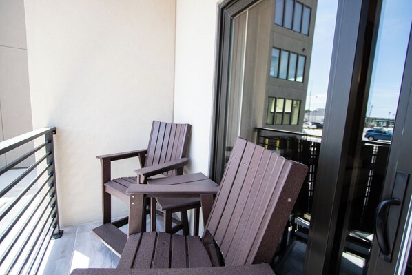 A balcony with two Adirondack chairs and a small table.