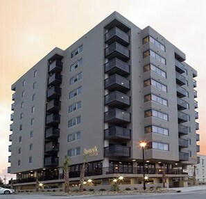 A multi-story hotel with balconies, a ground-level restaurant, and a clear view of the sky.
