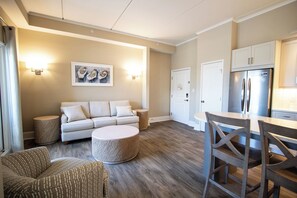 A modern living room with a sofa, round coffee table, and a dining area with chairs and a table.
