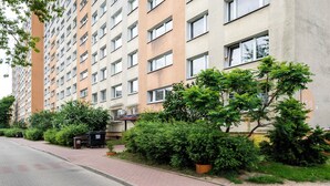 Un immeuble résidentiel à plusieurs étages, doté d’un chemin piétonnier pavé et d’espaces verts.