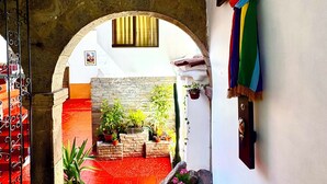 A narrow passageway with a red-tiled floor, an archway, and a staircase with a metal railing. - Cusi Guest House (Cusco)
