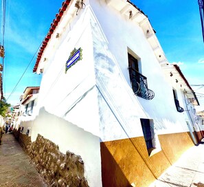 A white building with a red-tiled roof, a balcony, and a small window. - Cusi Guest House (Cusco)