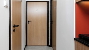 Ein Korridor mit einer Holztür, einem schwarzen Türrahmen, einer weißen Wand und einer roten Akzentwand.