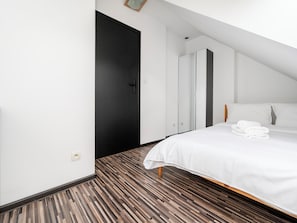A modern hotel room with a large bed, a black door, and a wardrobe. - Stawy Jana Apartment #14 (Łódź)