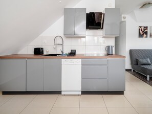 Eine moderne Küche mit grauen Schränken, einem Geschirrspüler, einer Kaffeemaschine und einem Wasserkocher.