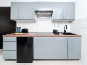 Eine moderne Küche mit grauen Schränken, einem schwarzen Geschirrspüler, einer Kaffeemaschine und einem Toaster.