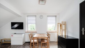 Eine moderne Küche mit Esstisch, Stühlen, Fernseher und einem schwarzen Kühlschrank.
