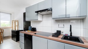 Eine moderne Küche mit grauen Schränken, einem schwarzen Geschirrspüler und einer Holzarbeitsplatte.