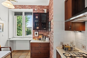 Eine Küche mit Backsteinwand, Holzschränken, einem Fenster und einem Gasherd.
