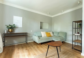 Una sala de estar con un sofá azul claro, una mesa de centro, una consola con una planta y una cita enmarcada en la pared.