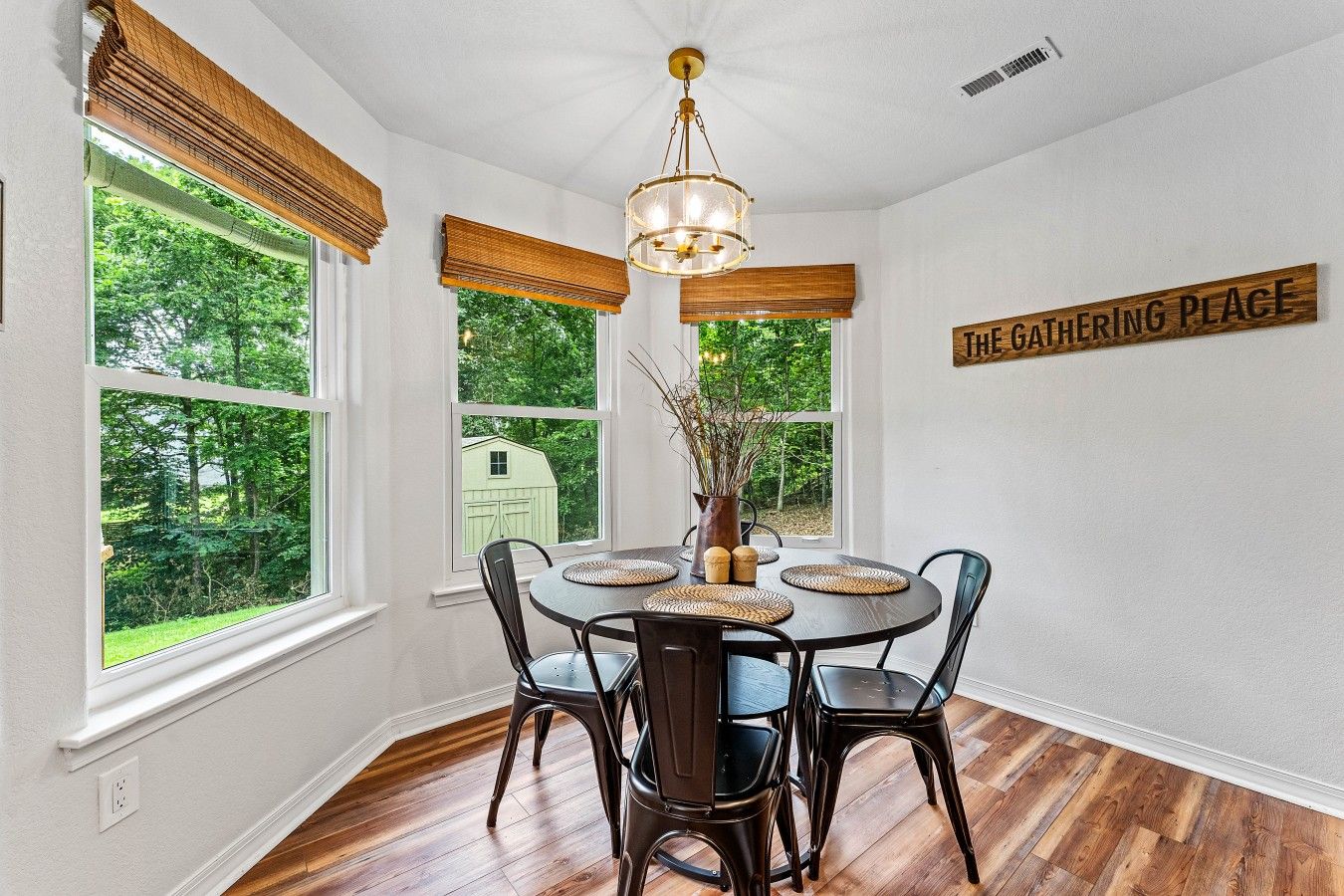 A dining area with a round table, chairs, a chandelier, and a sign reading 'The Gathering Place'.