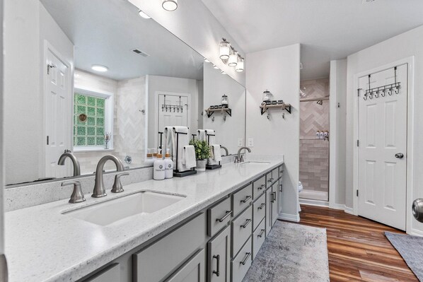 Un bagno moderno con un ampio lavabo, due lavandini, uno specchio e una zona doccia.
