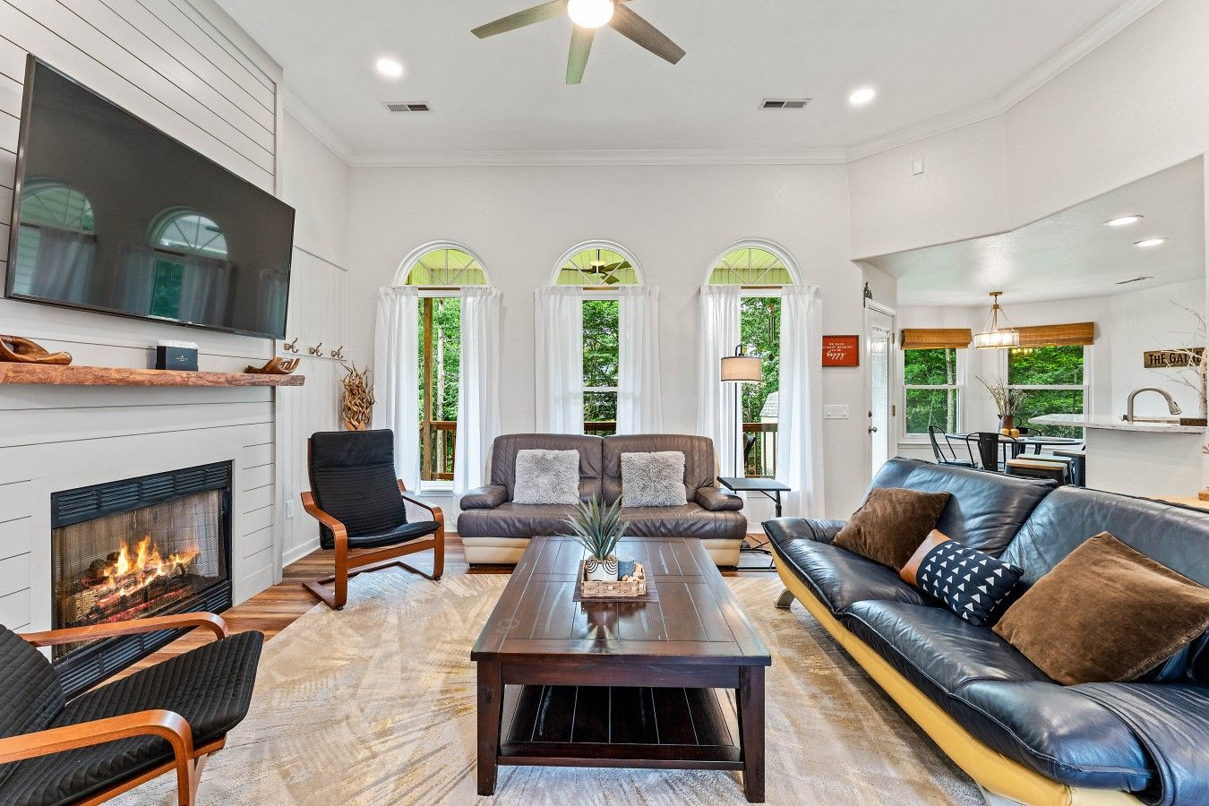 A modern living room with a fireplace, leather sofas, a coffee table, and large windows.